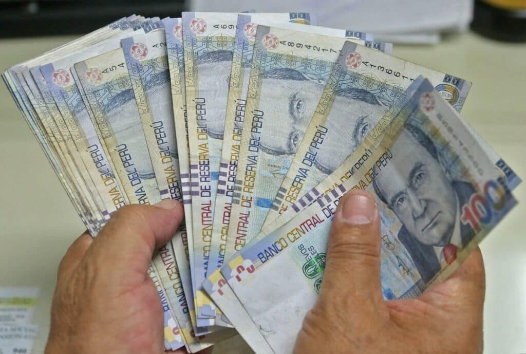 manos con billetes de cien soles peruanos